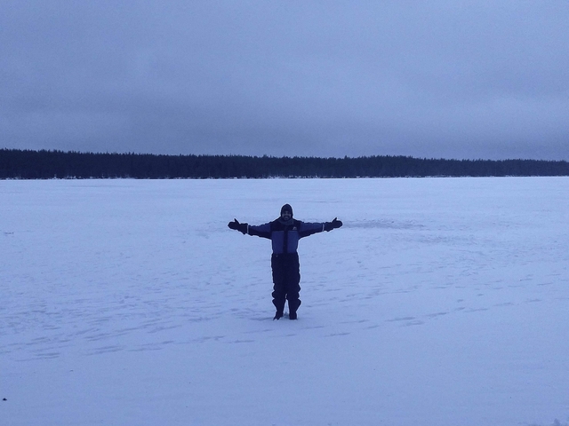 Person with arms outstretched on a vast snowy landscape.