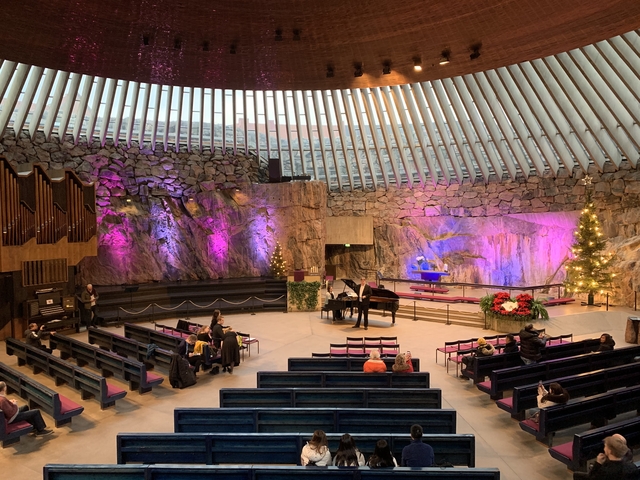 Concert hall with natural rock walls and a piano.