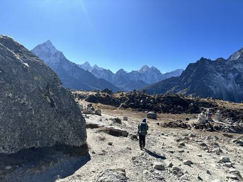 Hiker on a rocky trail in a mountainous landscape.