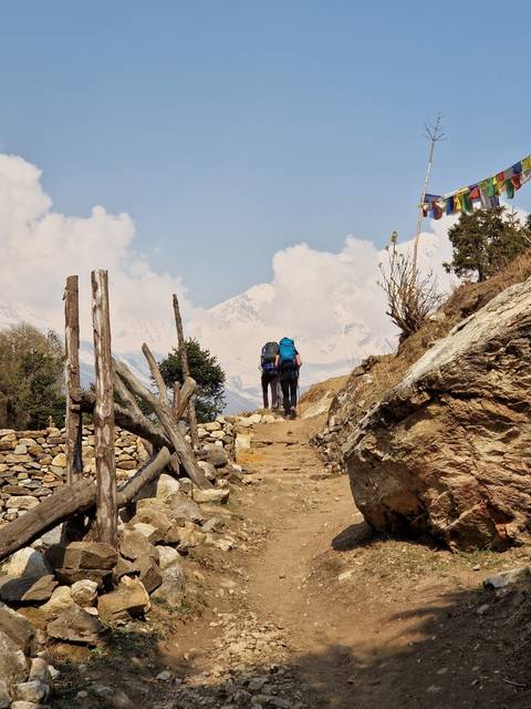       Hikers on a rugged trail with distant mountains.
  