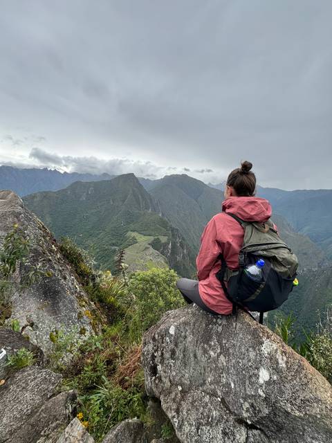 Person sitting on a rock overlooking a valley.