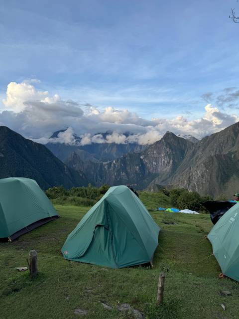 Tents set up on a grassy hill with mountain views.