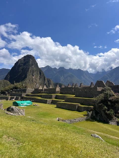 Terraced grass and stone ruins with mountain backdrop.