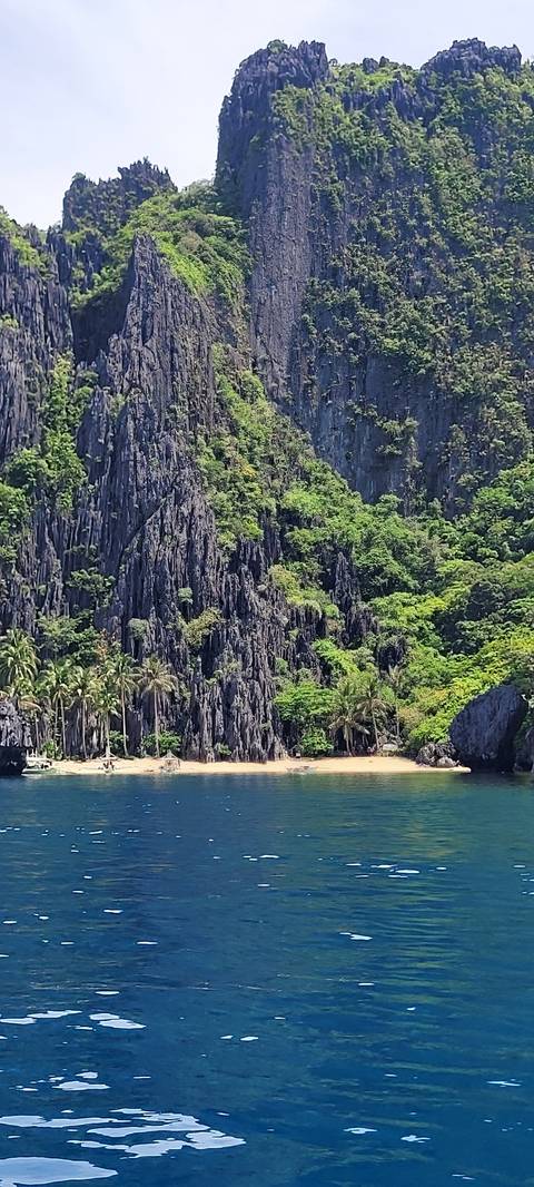       Secluded beach with rocky cliffs and clear blue sea.
  