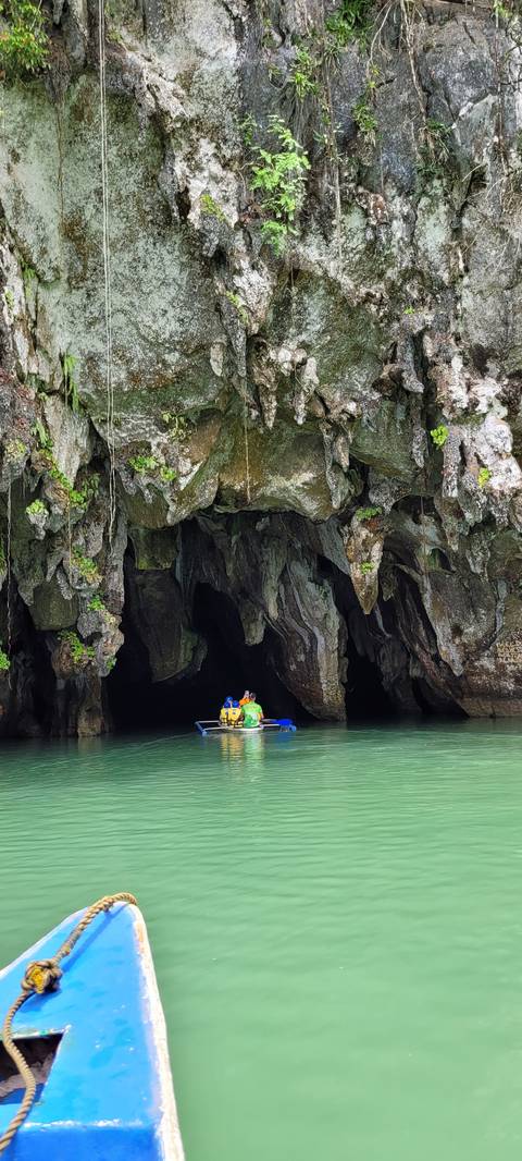       Person in a small boat entering a cave.
  