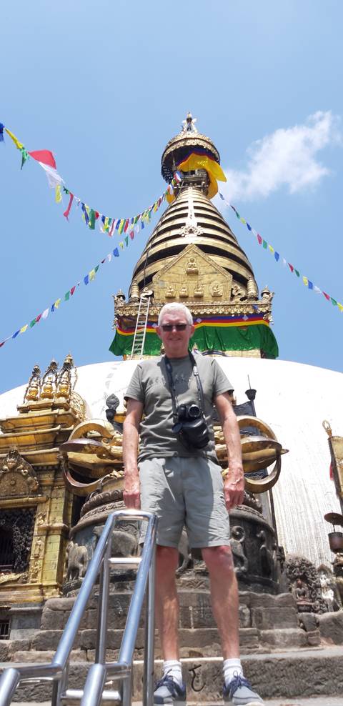       A person standing in front of a stupa with prayer flags.
  
