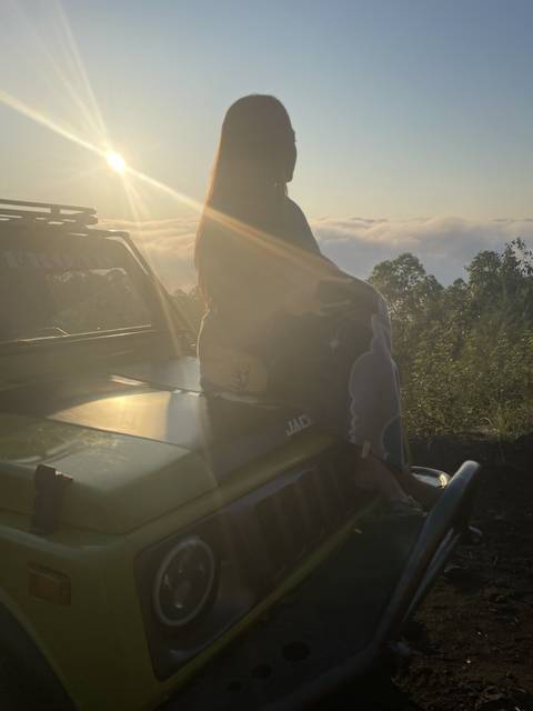 Person sitting on a vehicle at sunset.