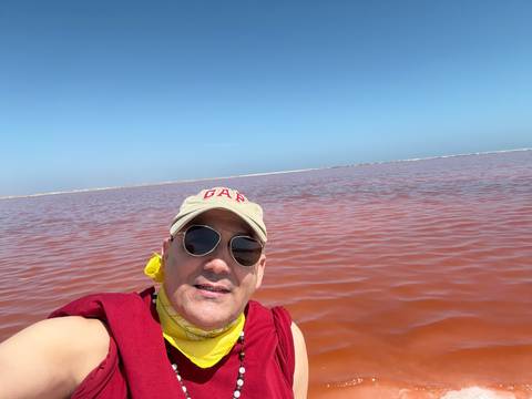       Person taking a selfie by a red lagoon.
  