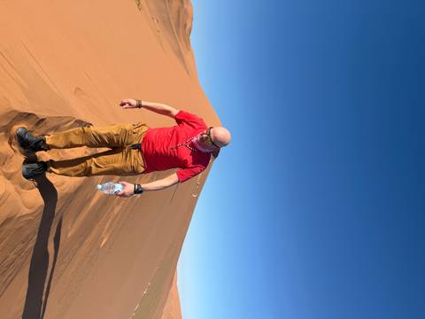       Person climbing sand dune with water bottle.
  