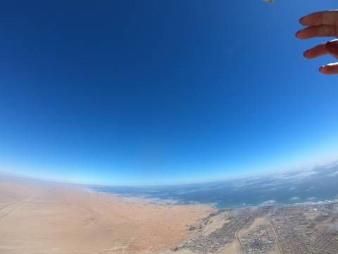       View of coastline and dunes with the ocean and blue sky.
  