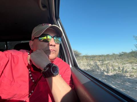       Person in a car, wearing sunglasses with a reflection of the sky.
  
