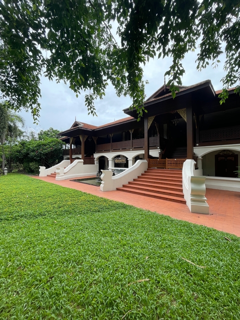       Traditional wooden building with red steps and green lawn.
  