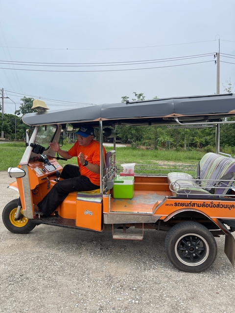       Person sitting in a tuk-tuk vehicle parked outside.
  