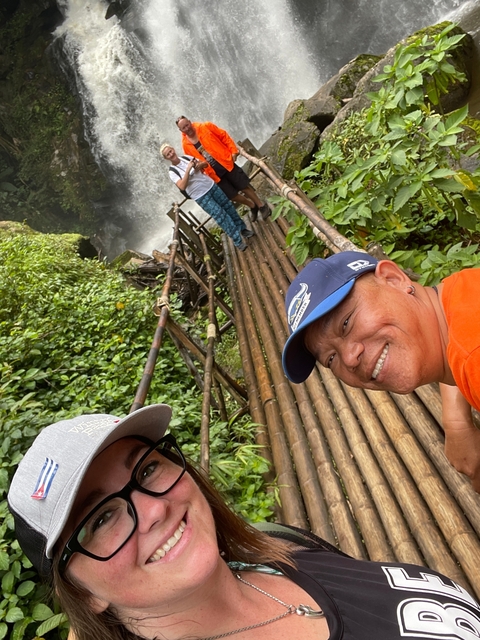       People standing on a bridge over a waterfall.
  