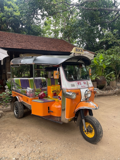      Orange tuk-tuk parked outdoors near a building.
  