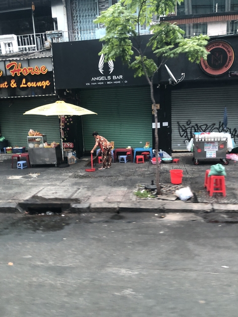 Person cleaning the pavement in an urban street setting.