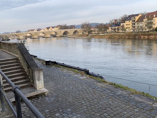 Stone bridge over a wide river with buildings along the bank.