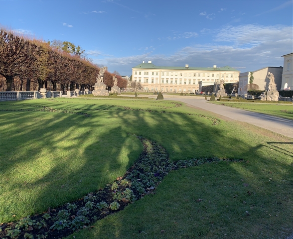 Well-maintained garden with statues and a historic building in the background.