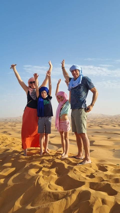       Family posing in the desert with children raising their hands
  