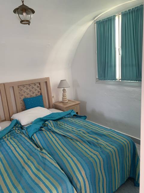 Interior of a room with a bed and a small window.