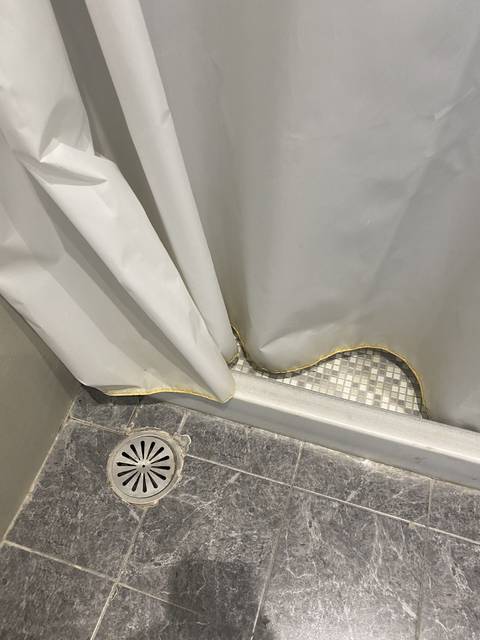 Shower area with curtain and drainage.
