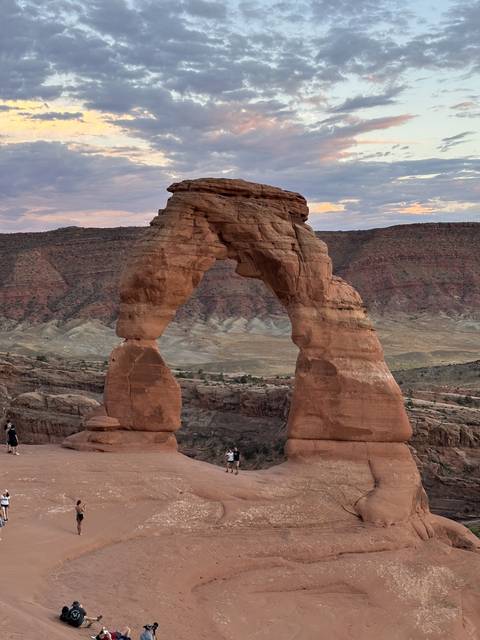       Delicate Arch with people at the base in a desert landscape.
  