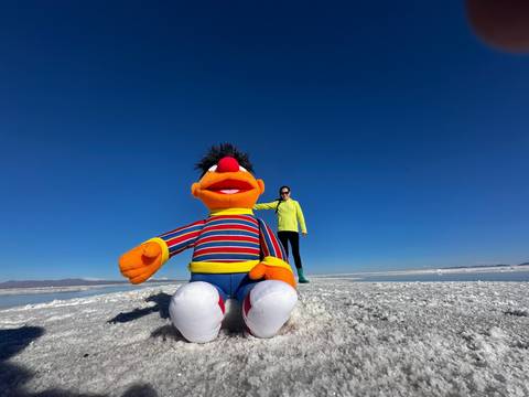 Toy figure at Uyuni Salt Flats with a person in the background.