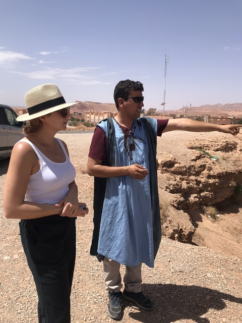       Two people standing and pointing in a desert landscape.
  