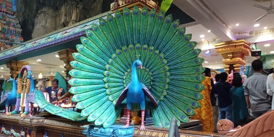Statue of a peacock with people in a decorated interior.