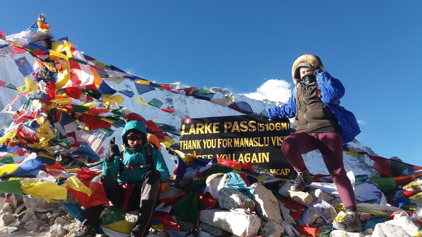 Two people posing at Larke Pass with prayer flags.