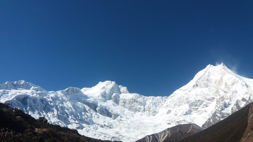 Mountain range with snow under clear blue sky.