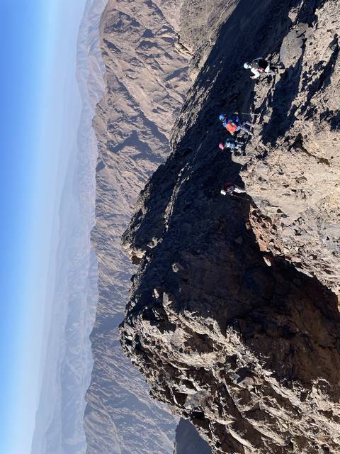       Hikers on a steep rocky mountain path.
  