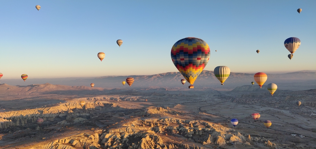 Hot air balloons floating over a scenic landscape at sunset.