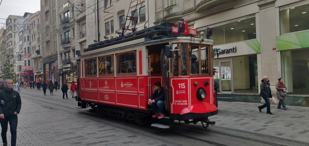 Red vintage tram in a bustling street.