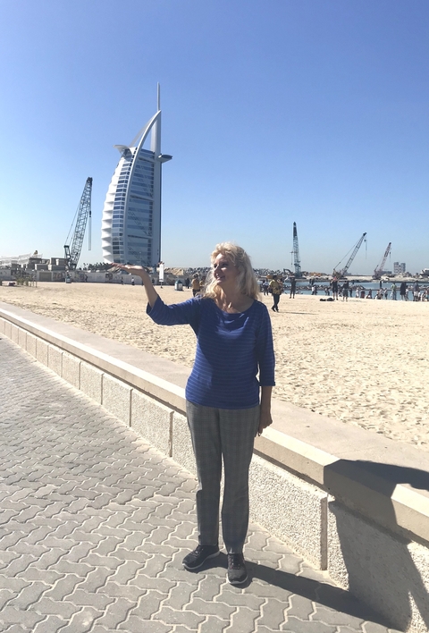       Woman posing near a beach with skyscraper in the background.
  