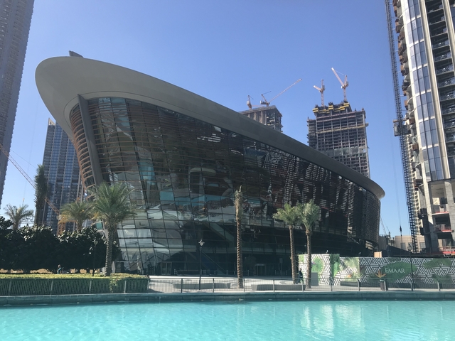 Modern building with glass facade and construction cranes in the background.