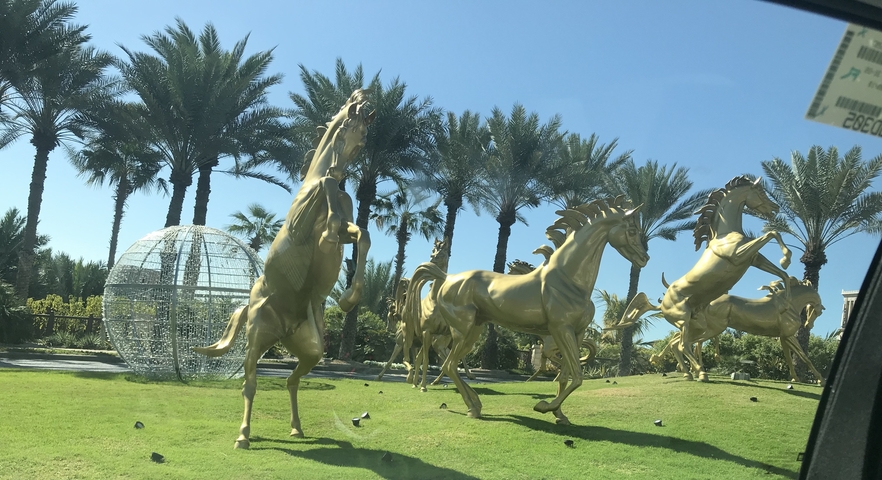 Golden horse statues in a garden setting.