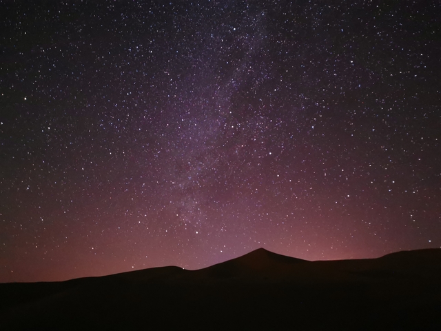       Starry night sky over sand dunes.
  