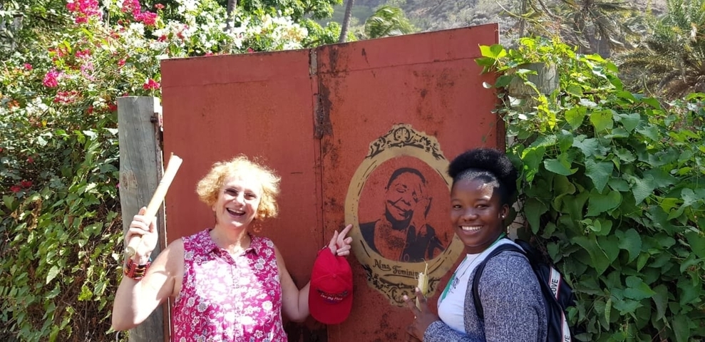       Two people smiling in front of a decorated gate.
  