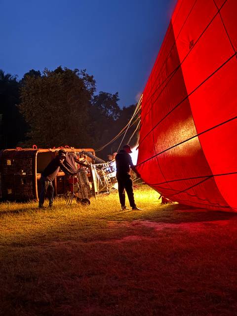       People preparing a hot air balloon for flight during twilight.
  