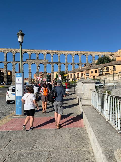 People exploring an aqueduct with blue sky.