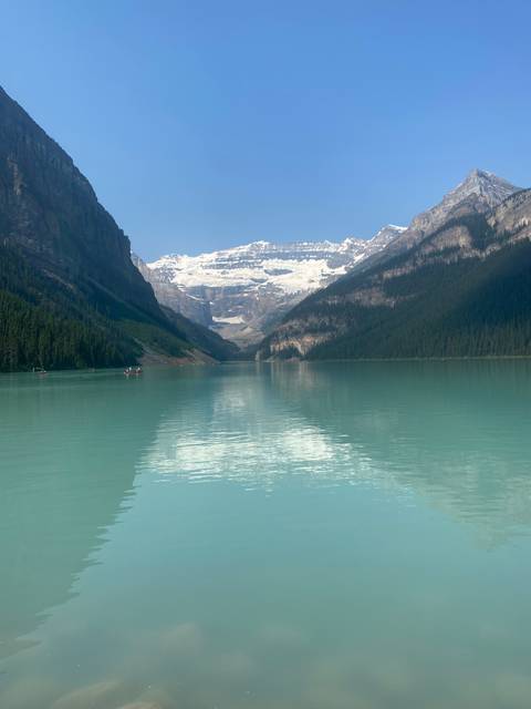 A lake surrounded by mountains with a reflection on the water.