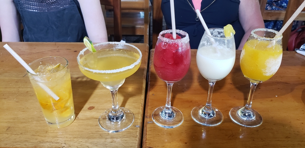       Assorted cocktails on a wooden table.
  