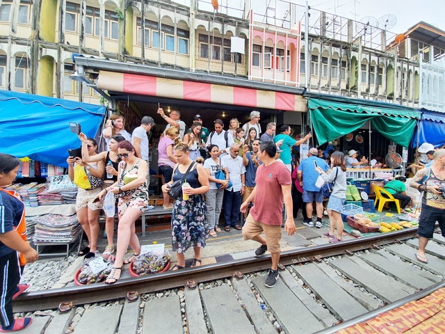 Crowded market scene on railway tracks with people and goods