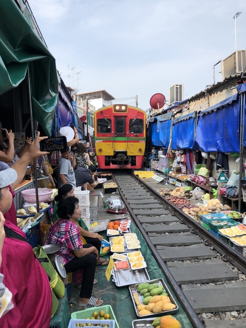 Train passing through a busy market with people selling goods