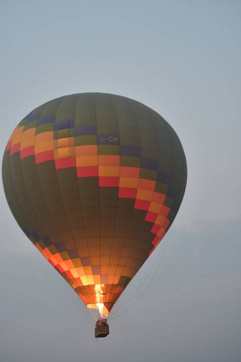       Hot air balloon inflating against a clear sky.
  