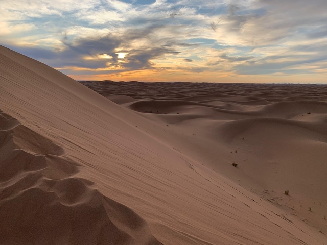       Sand dunes with a dramatic sky at sunset.
  