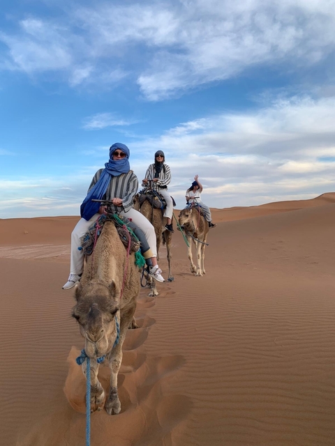       A group of people riding camels in the desert.
  