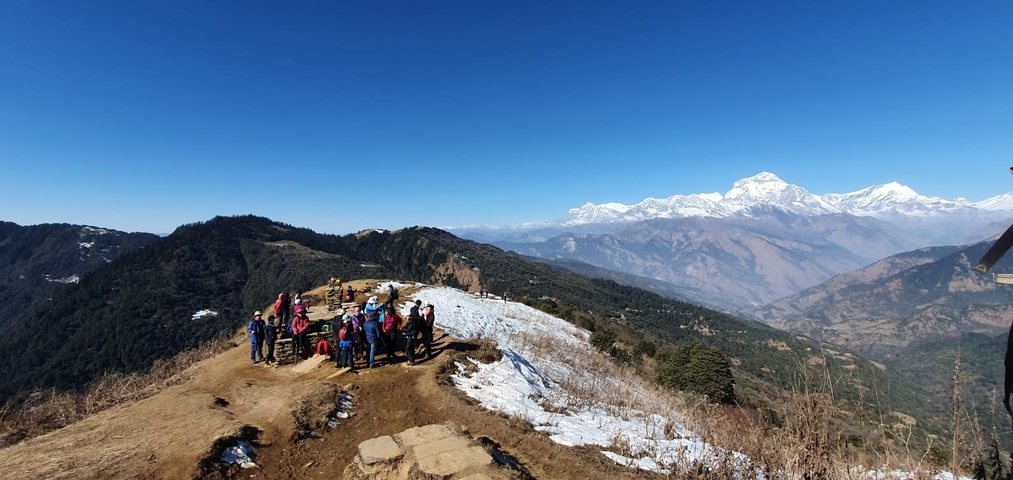       Group of hikers on a mountain trail with mountains in the background.
  