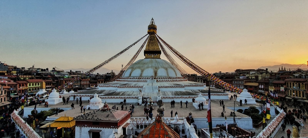       A large stupa with prayer flags at sunset.
  